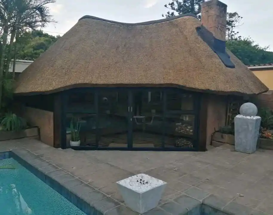 Finished thatched pool lapa with glass doors and a stone wall